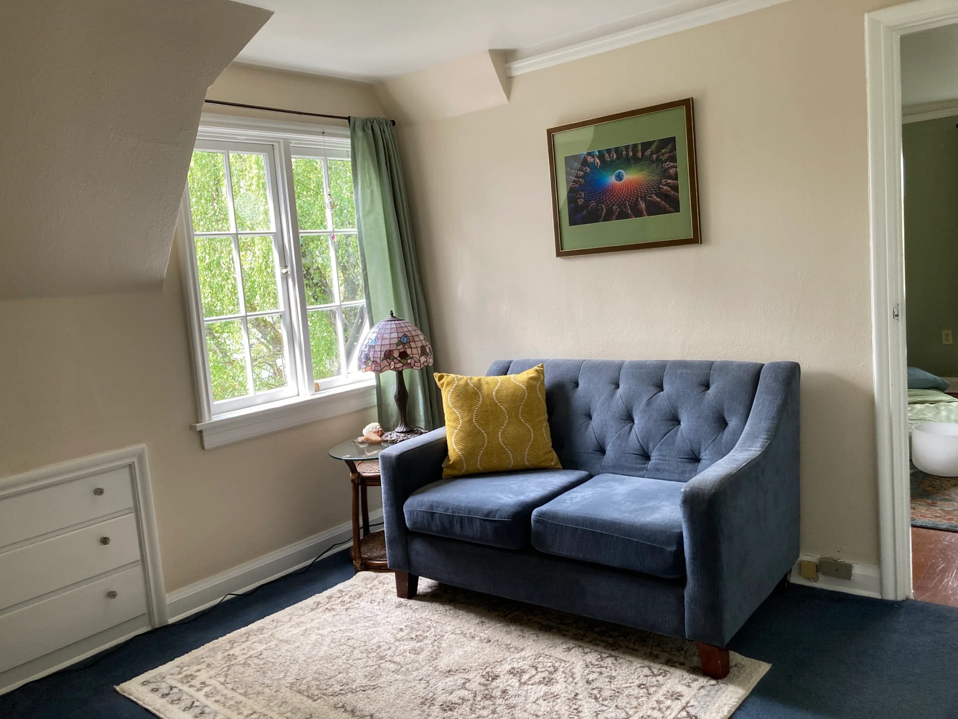 light refracting onto the wall over a comfortable couch with a yellow patterned pillow